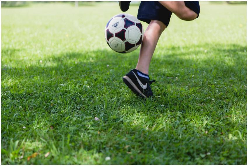A child skillfully kicks a soccer ball on a sunny