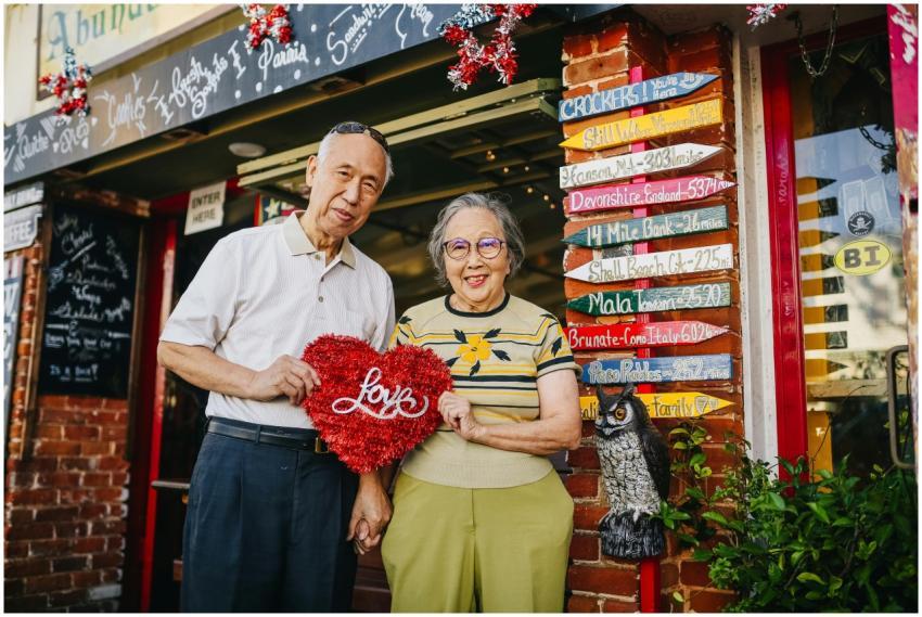 Senior couple holding a heart symbol outside a col