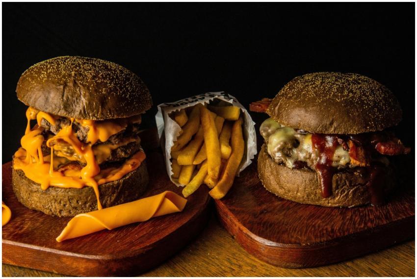 Close-up of two gourmet cheeseburgers with fries o