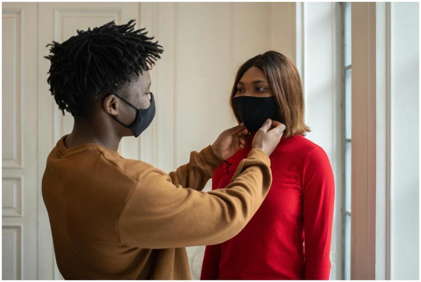 A couple indoors adjusting protective masks, highl