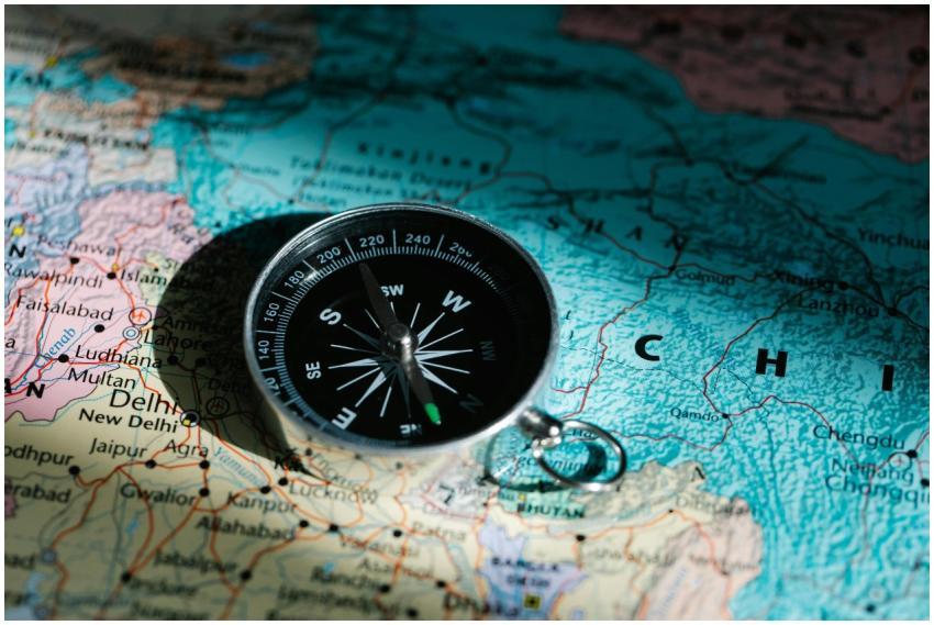 A compass resting on a map of China and India sign