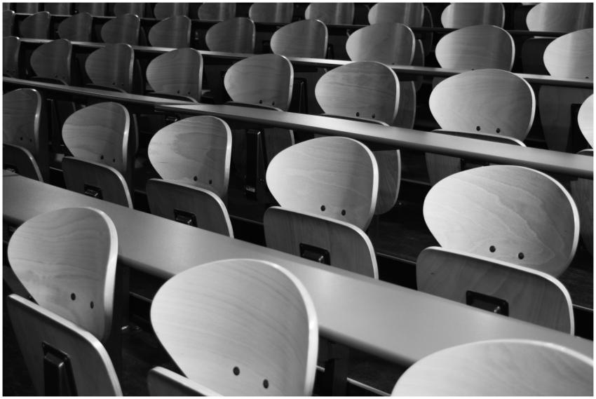 A monochrome view of empty wooden seats in a spaci