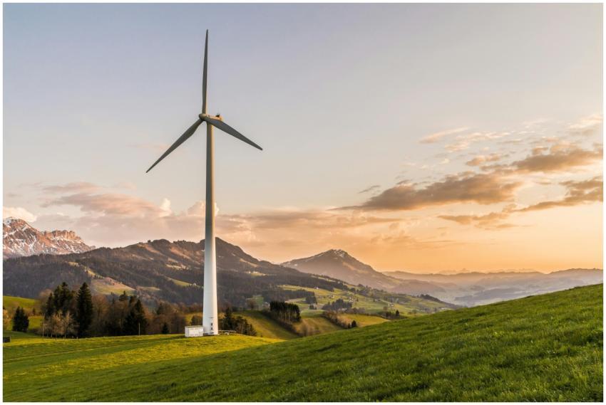 Wind turbine amid rolling hills and mountains at s