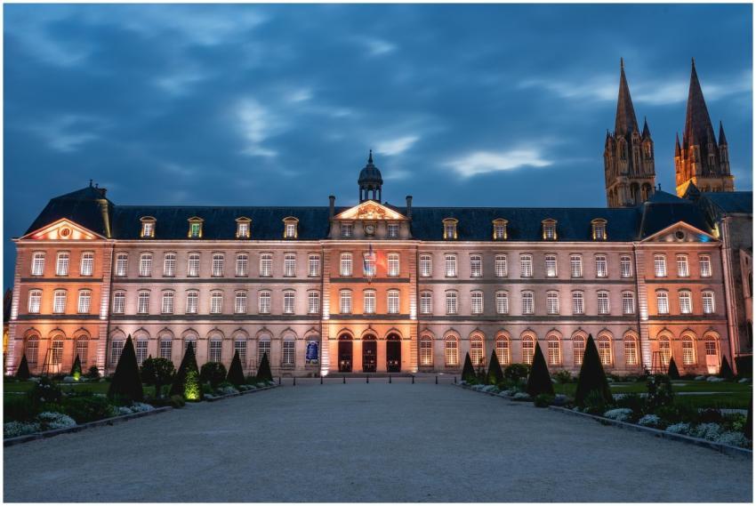 Illuminated facade of a historic abbey at dusk in