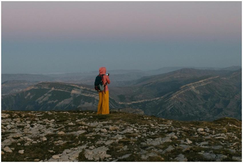 A woman in a hijab and bright pants overlooks a va
