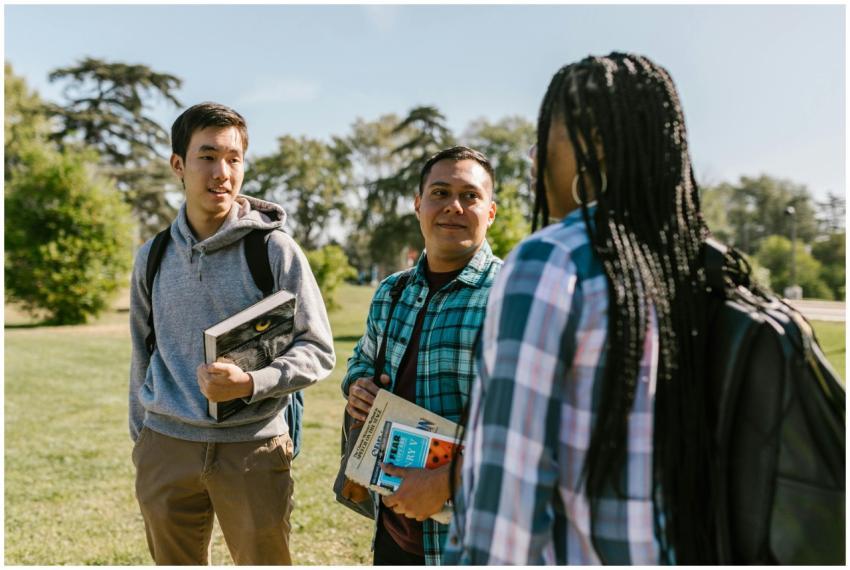 Group of students chatting outdoors with books on