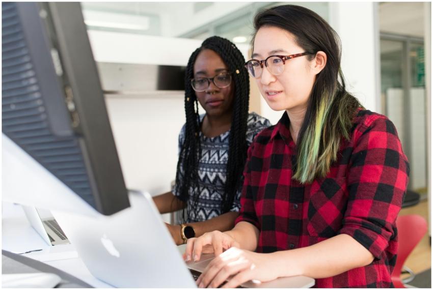 Two women working on a computer project together i