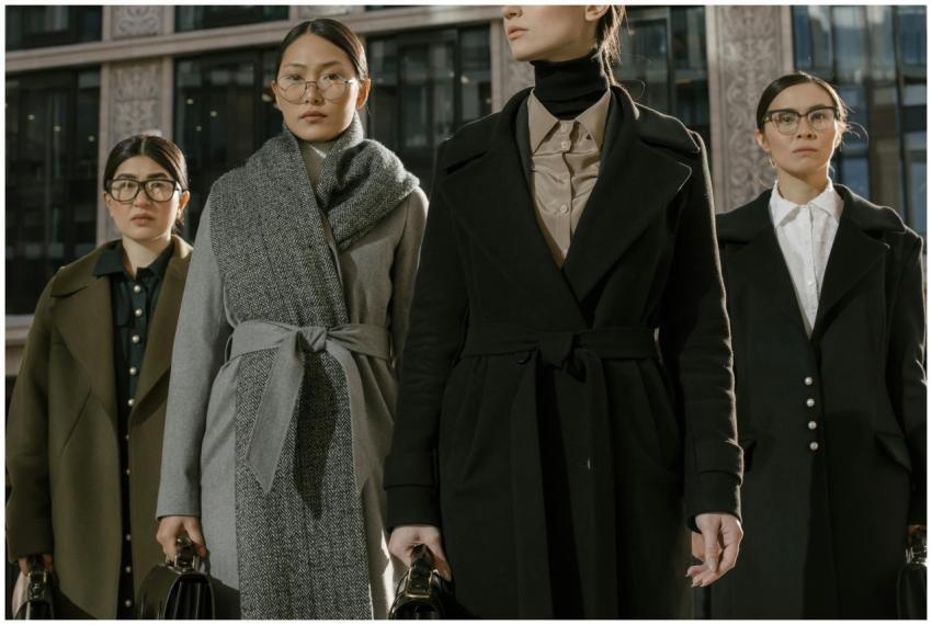 A group of fashionable women in coats standing con