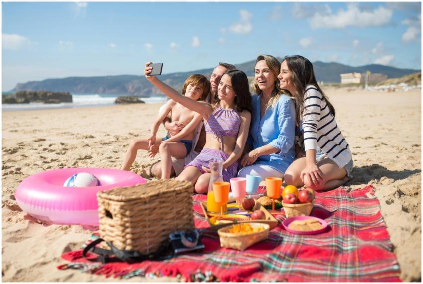Family takes a selfie while enjoying a beach picni