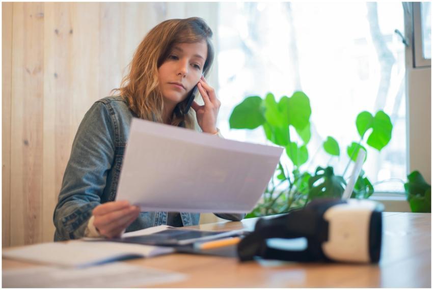 Businesswoman reviewing paperwork while on a call