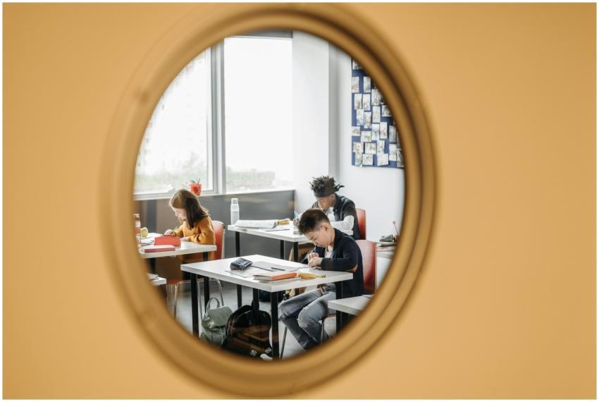 Three students focusing on studies in a classroom,
