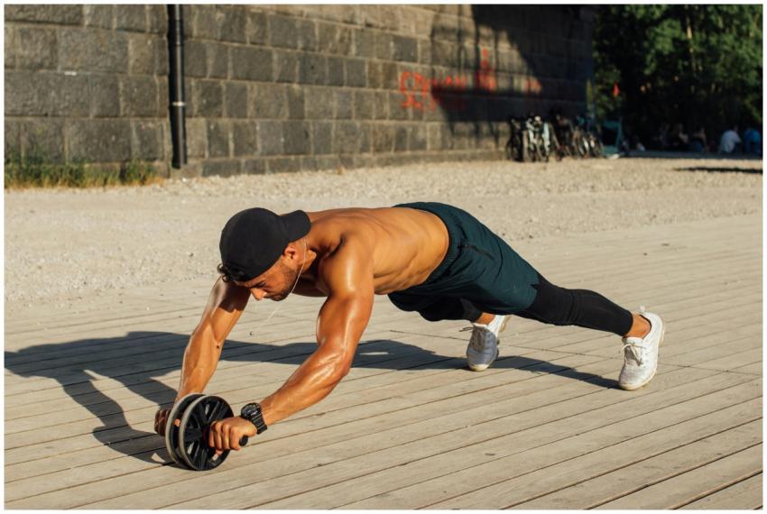 Fit man in outdoor workout using ab roller, showca