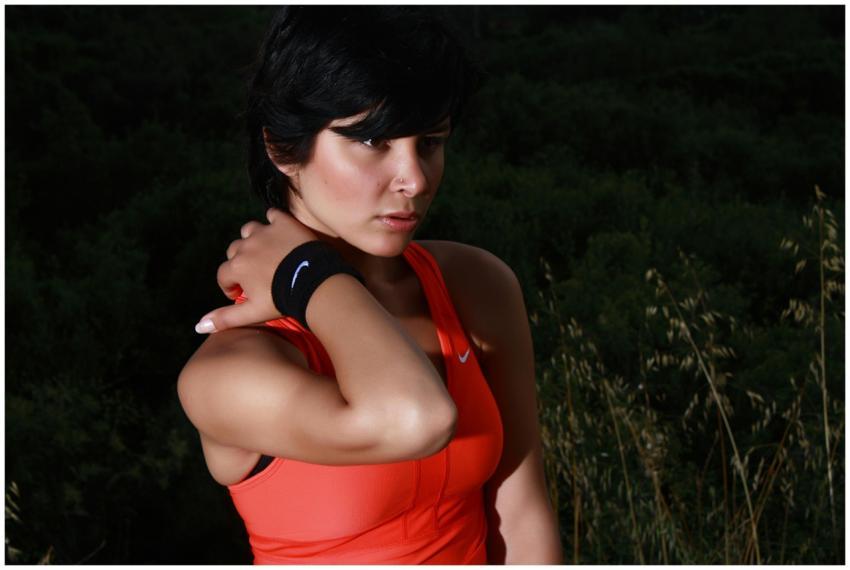 A woman in athletic wear posing outdoors against a