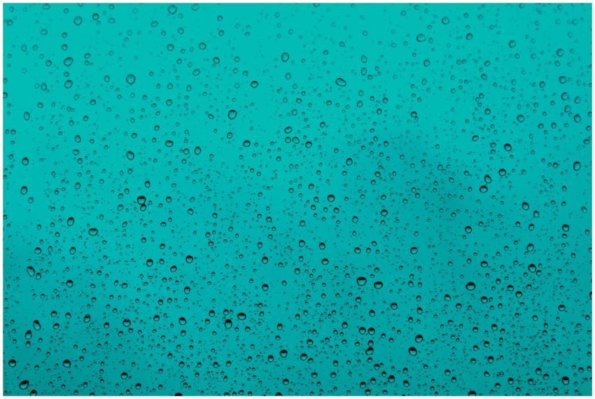 Close-up of water droplets on a teal glass window,