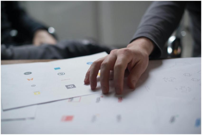 A close-up shot of a hand reviewing various logo d