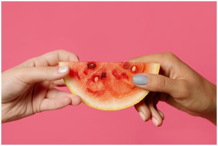 A close-up of two hands holding a slice of waterme