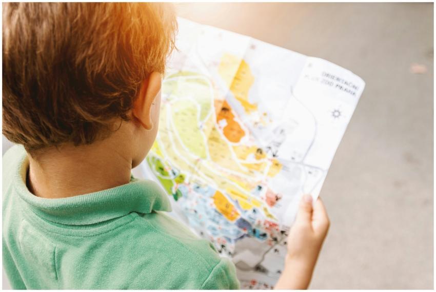 Young boy studying a colorful map outdoors in brig