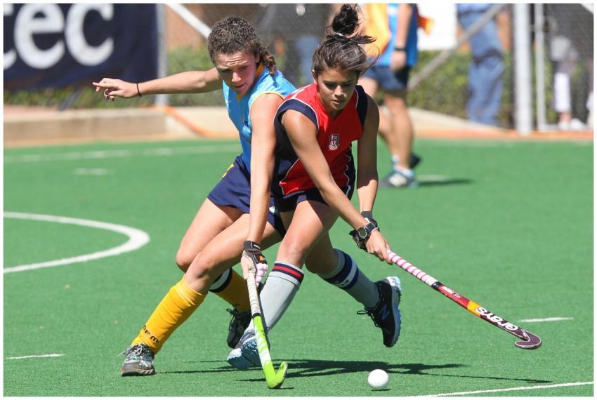 Two female field hockey players compete fiercely o