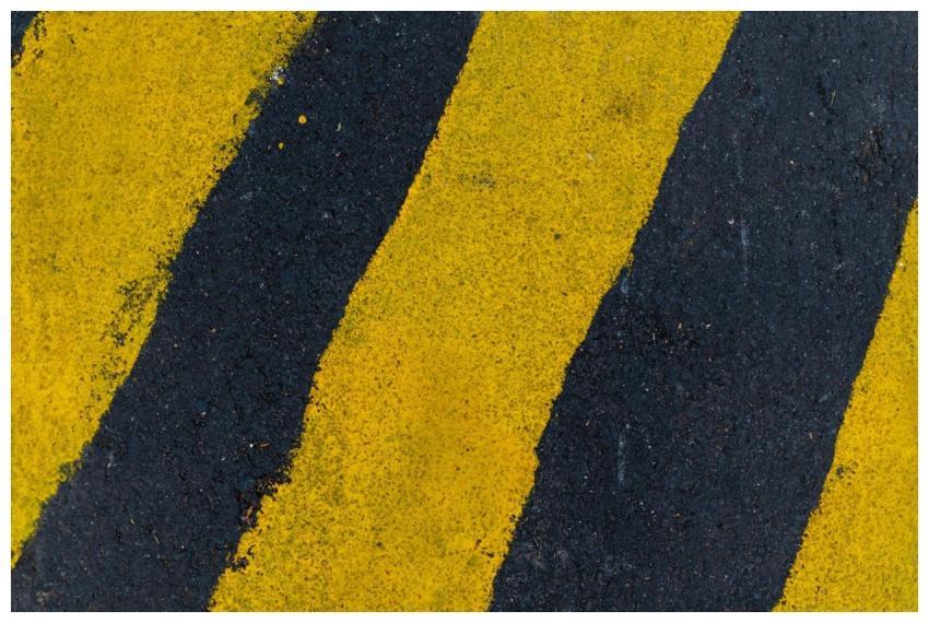 A high-angle close-up of yellow and black road mar