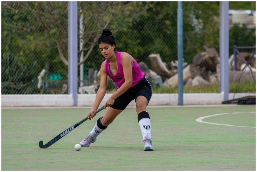 A young female athlete playing field hockey outdoo