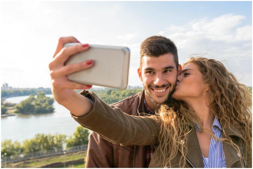A happy couple taking a romantic selfie by the sce