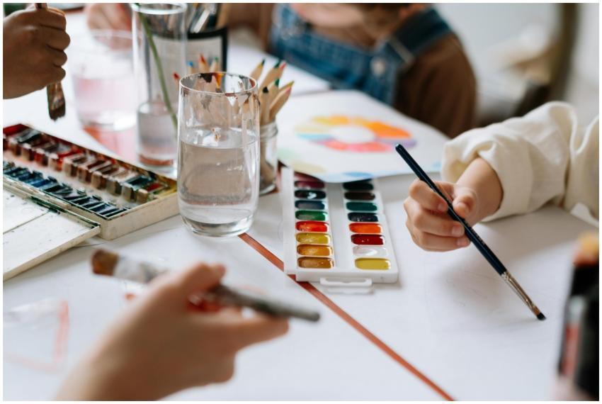 Children's hands holding paintbrushes while painti