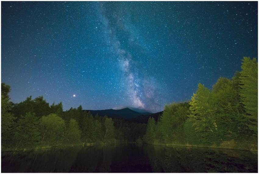 Stunning night sky with Milky Way over a serene fo