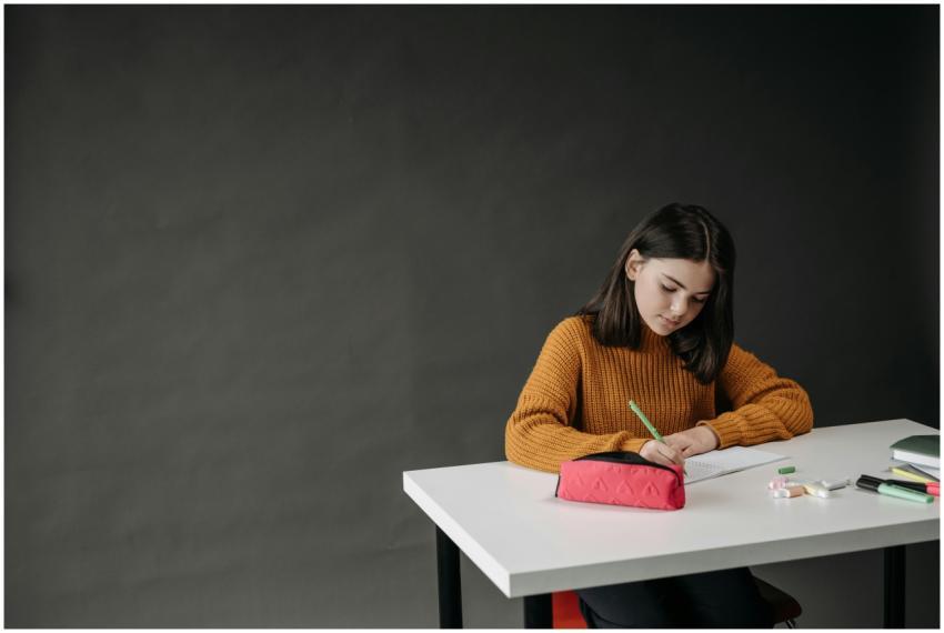 Focused young girl writing at a desk with school s