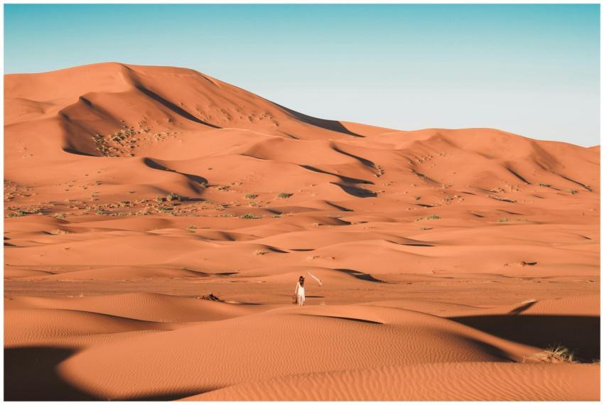 A lone person walking amidst the vast sand dunes o