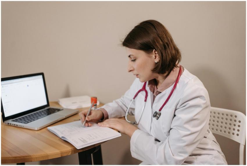 A female doctor in a lab coat writing a prescripti