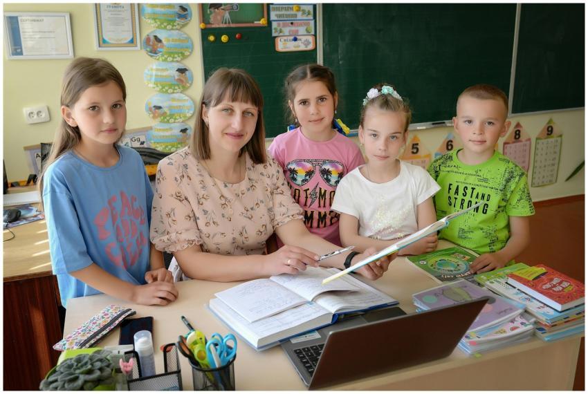 A teacher with four students in a classroom encour