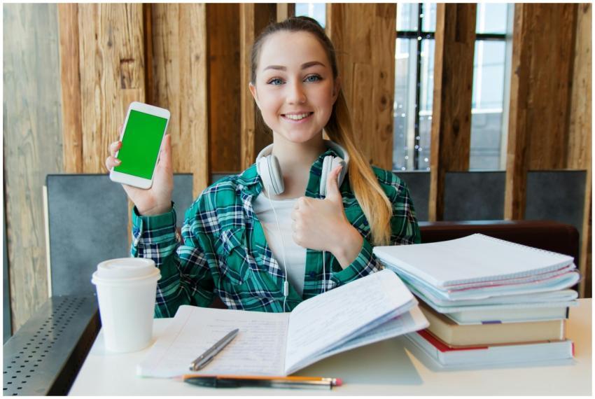 Smiling young woman using a smartphone while study