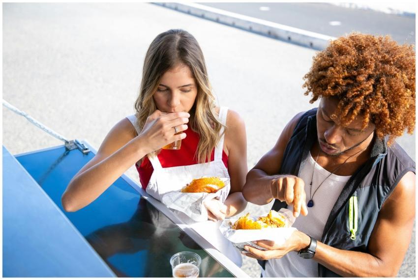 High angle of diverse couple eating unhealthy food