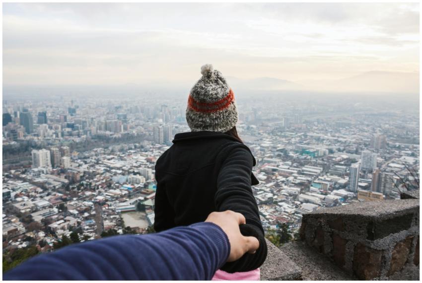 A couple holding hands overlooking a vast urban ci