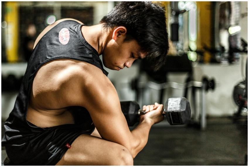 Young man intensely lifting a dumbbell in a gym, h