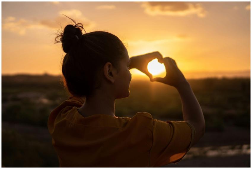 A silhouette of a young woman forming a heart shap