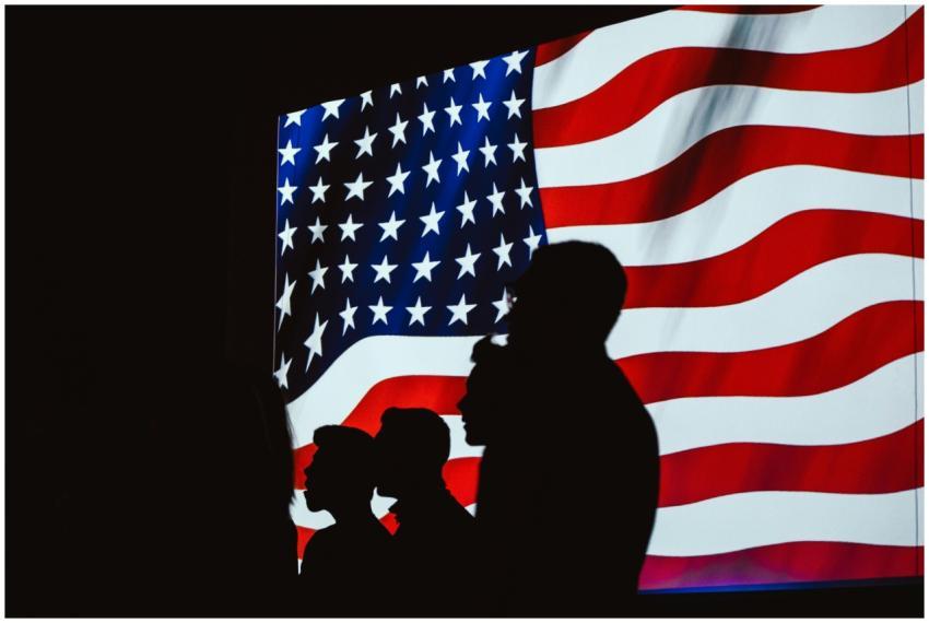 Silhouettes of people against a waving American fl