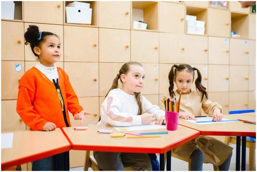 Three young girls in a classroom participating in