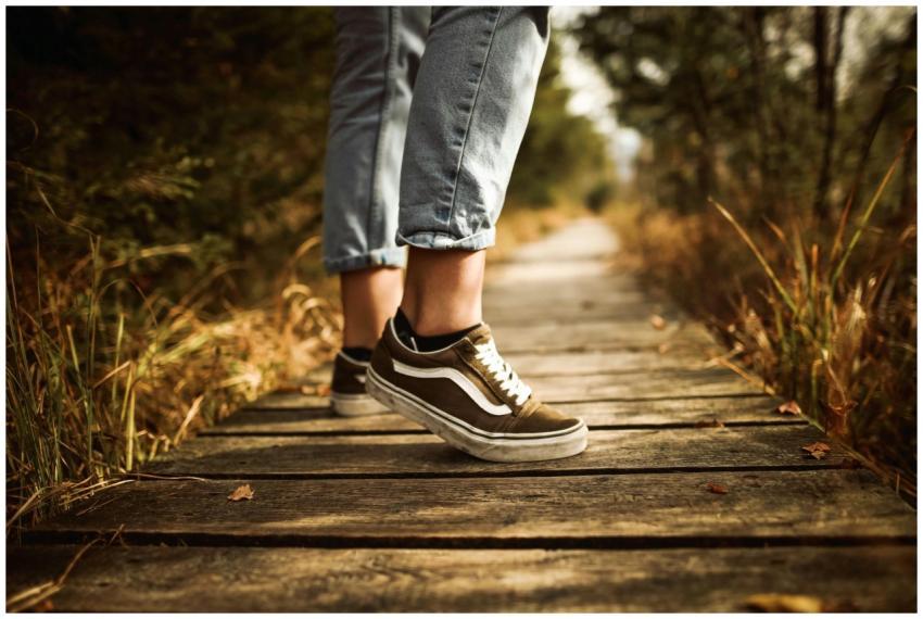 Close-up of a person walking on a wooden path in a