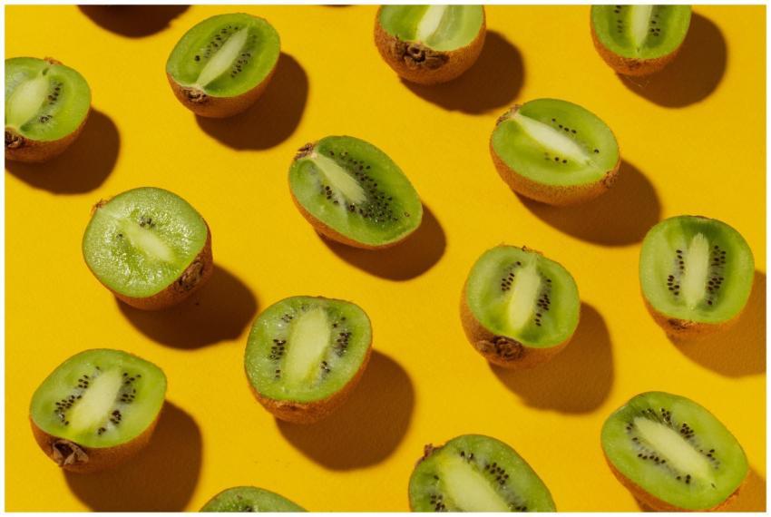 Freshly sliced kiwi fruits on a yellow surface sho