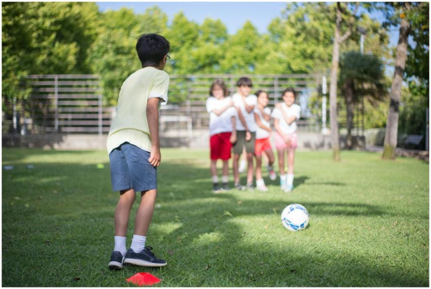 Group of children playing soccer in a sunny outdoo