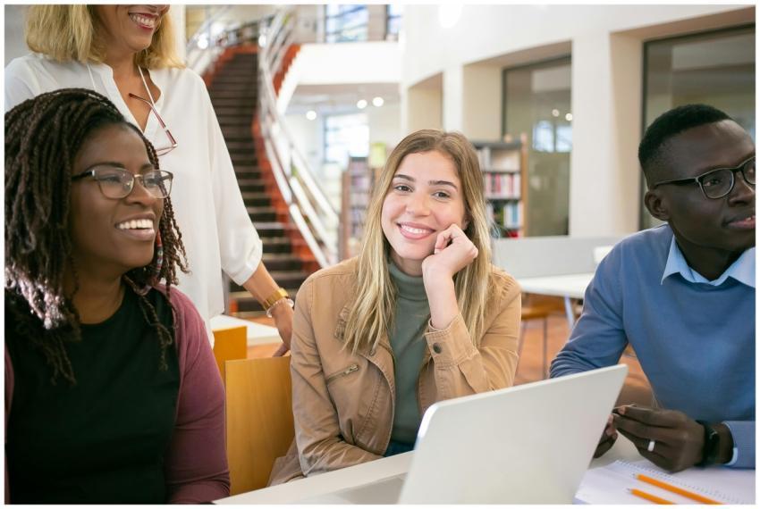 Cheerful multiracial young coworkers sitting at ta