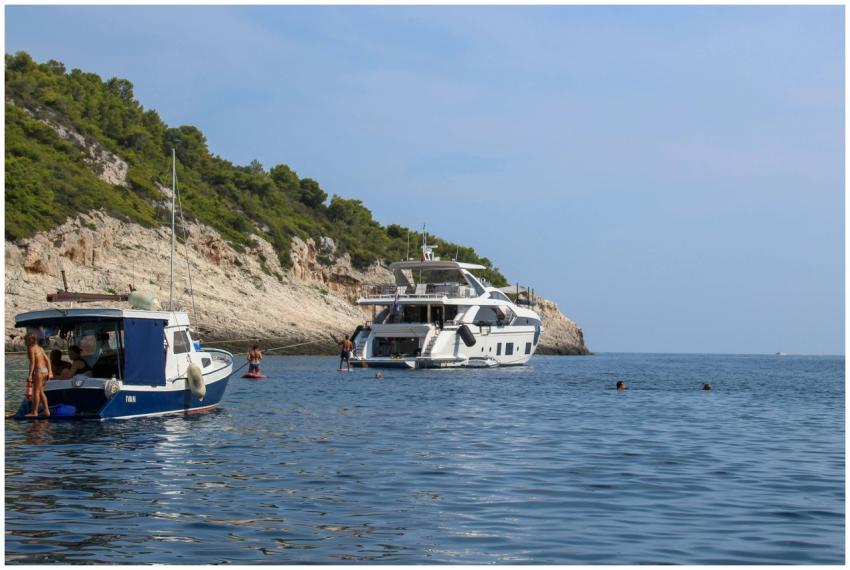 Luxury yachts anchored by a scenic rocky shoreline