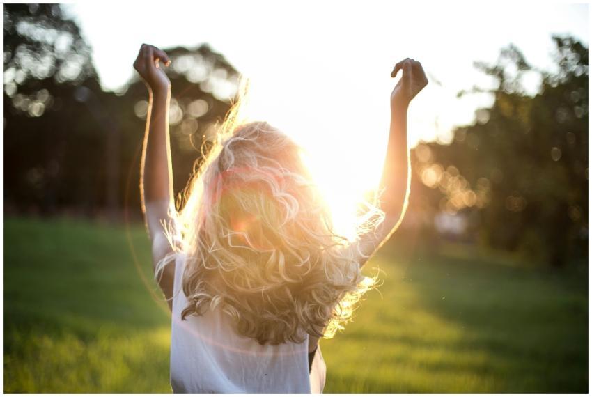 A woman with outstretched arms celebrates the suns