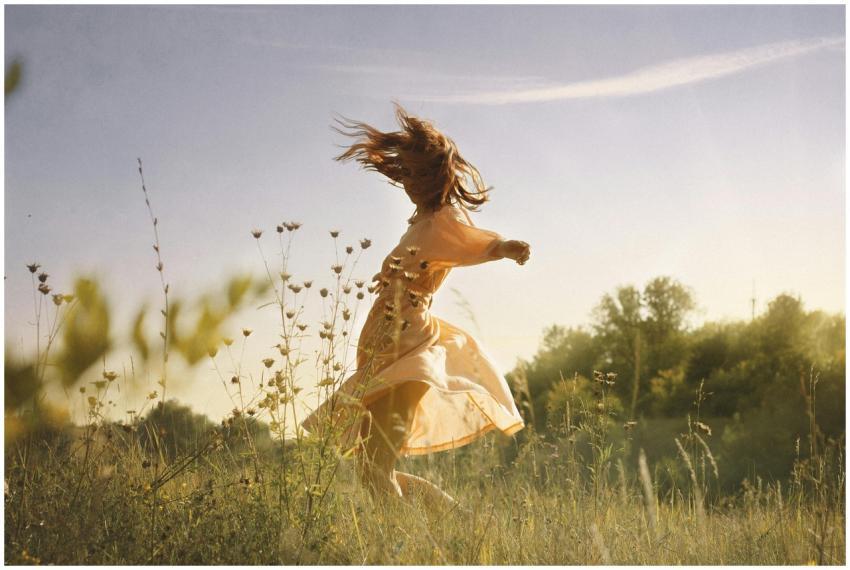A carefree young woman in a dress dances joyfully