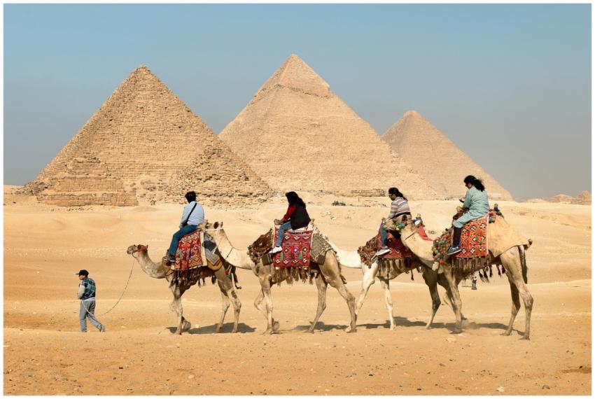 Tourists riding camels near the Great Pyramids of