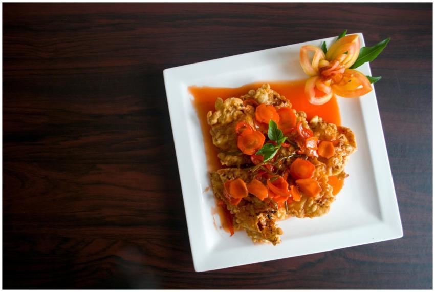 Crispy fried chicken topped with carrots and a flo