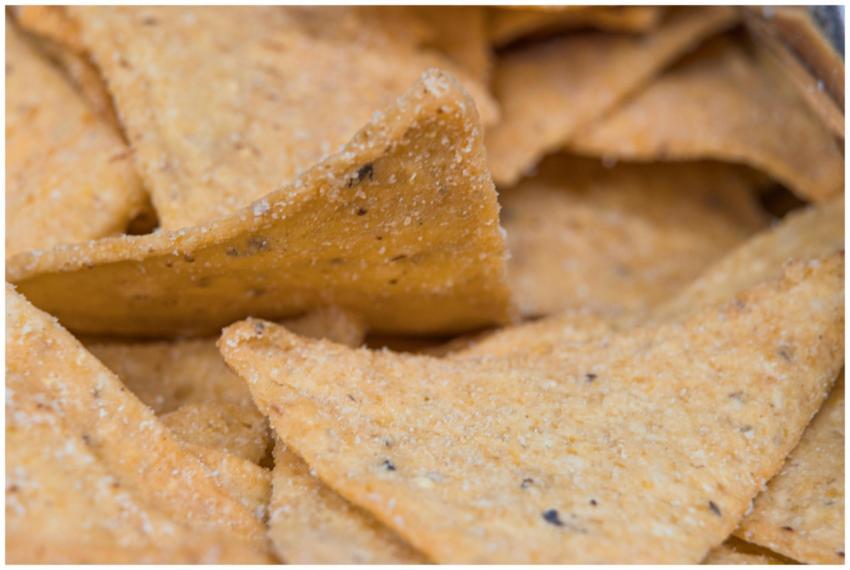 A macro shot of golden salted tortilla chips, show