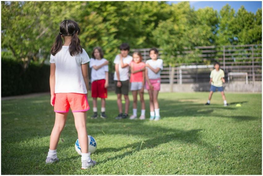 Group of kids playing soccer in a lush green park