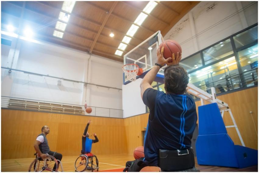 Athletes in wheelchairs playing basketball, emphas